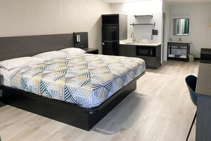 Une chambre d’hôtel équipée d’un lit, d’un bureau, d’un réfrigérateur, d’un lavabo et d’un miroir.