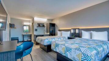 A hotel room with a bed, a desk, a chair, and a television.