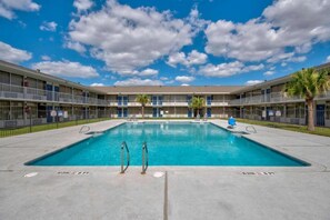 A swimming pool with a clear sky and a multi-story building with balconies. - 2 Full Beds | Mob Acc Tub Nsmk Kitchen (Rosenberg)