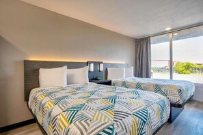 Et hotelværelse med to senge, et natbord og et vindue med udsigt.