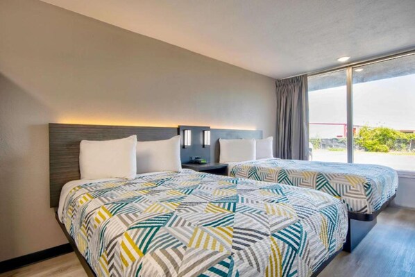 A hotel room with two beds, a nightstand, and a window with a view. - 2 Full Beds | Mob Acc Tub Nsmk Kitchen (Rosenberg)