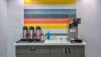 A kitchen area with a coffee machine, three thermos flasks, and a colorful tile backsplash.
