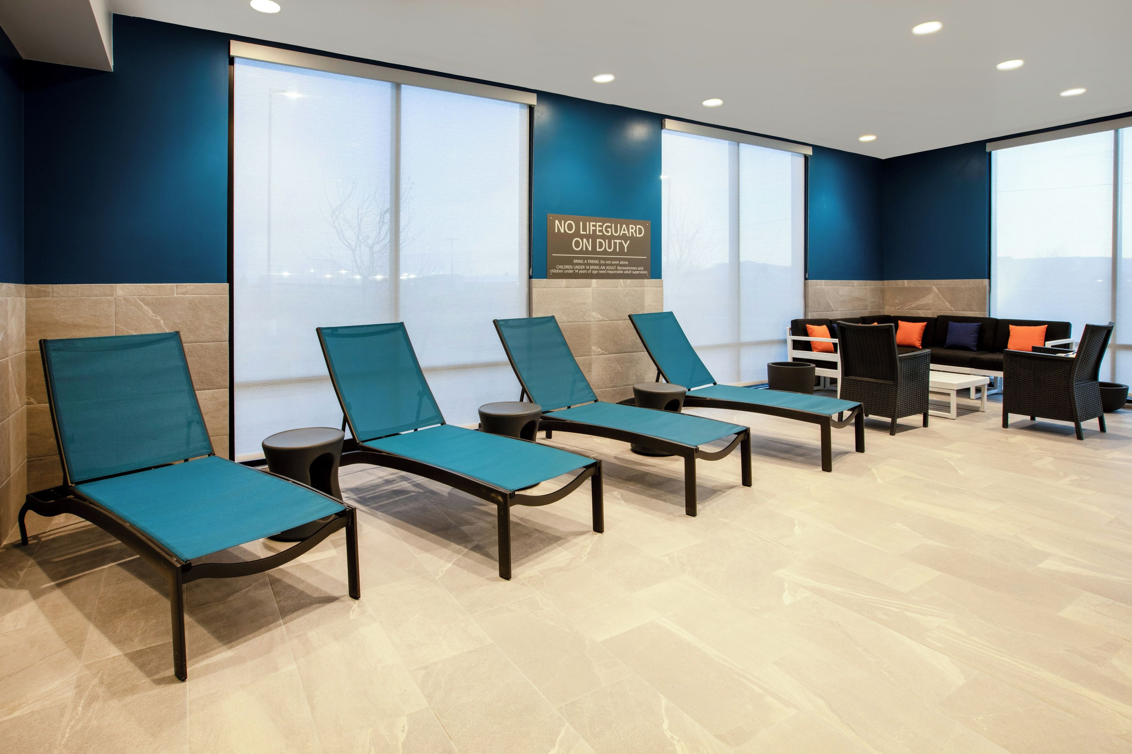 A waiting area with lounge chairs, a reception desk, and large windows.