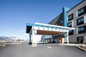Un edificio moderno con un área de entrada cubierta, un cartel que indica altura libre y una señal de bienvenida.