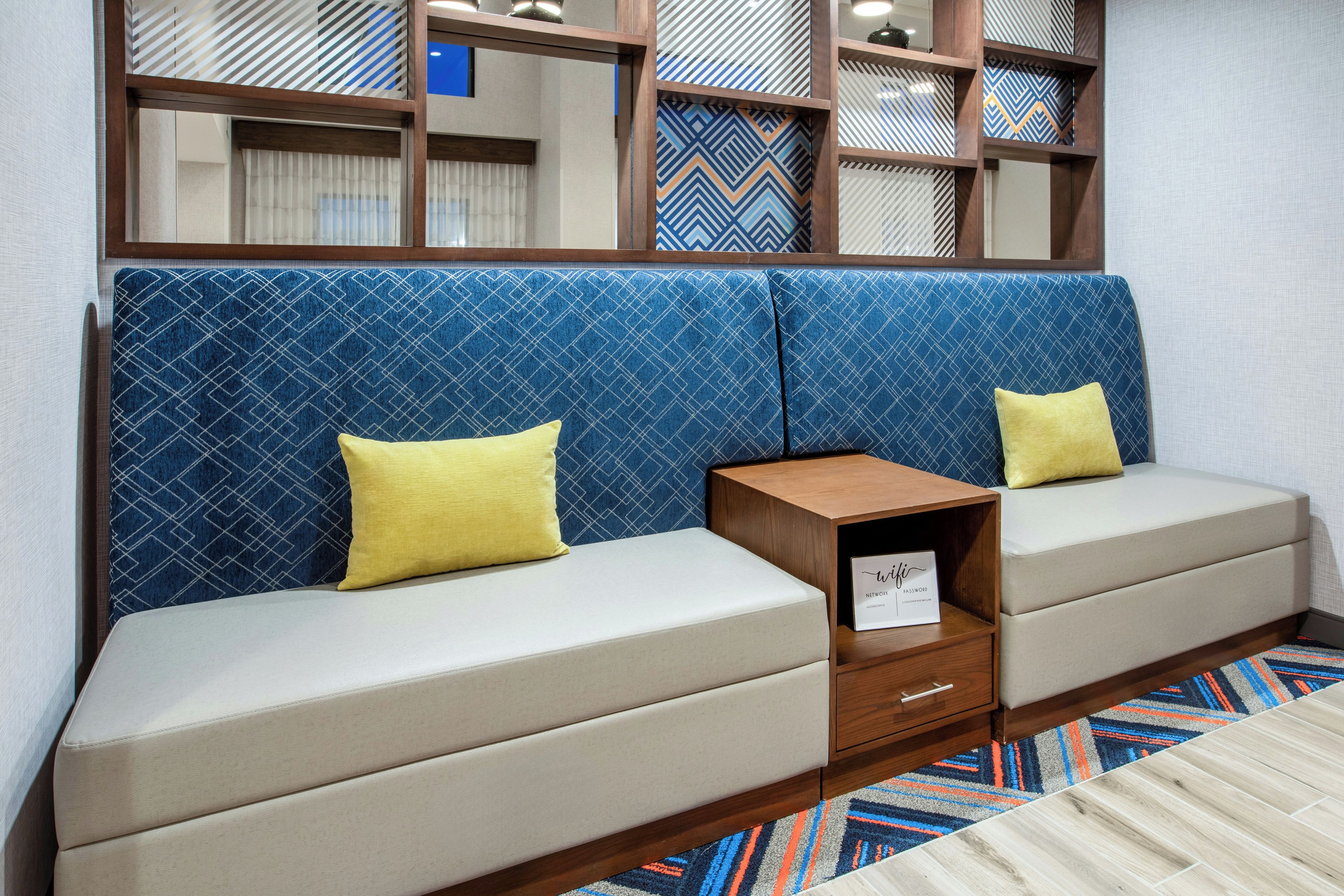 A room with a sofa set, a small wooden side table, and a patterned wall.