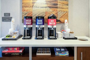Una estación de café con tres dispensadores: café descafeinado, tostado oscuro y agua caliente.