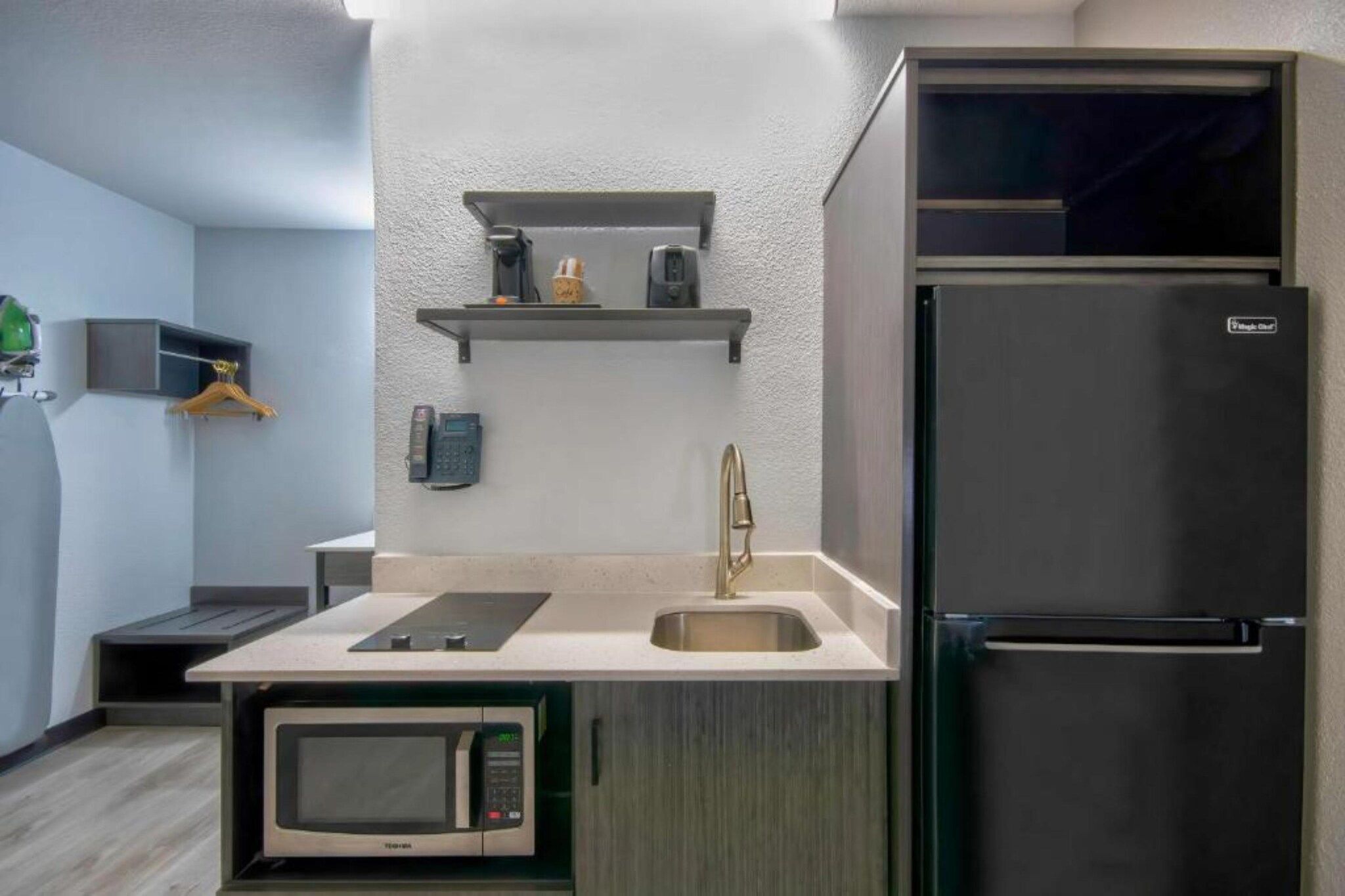 Une cuisine compacte équipée d’un four à micro-ondes encastré, d’un évier et d’un réfrigérateur.