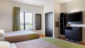 A hotel room with two beds, a wardrobe, a television, and a window with curtains.
