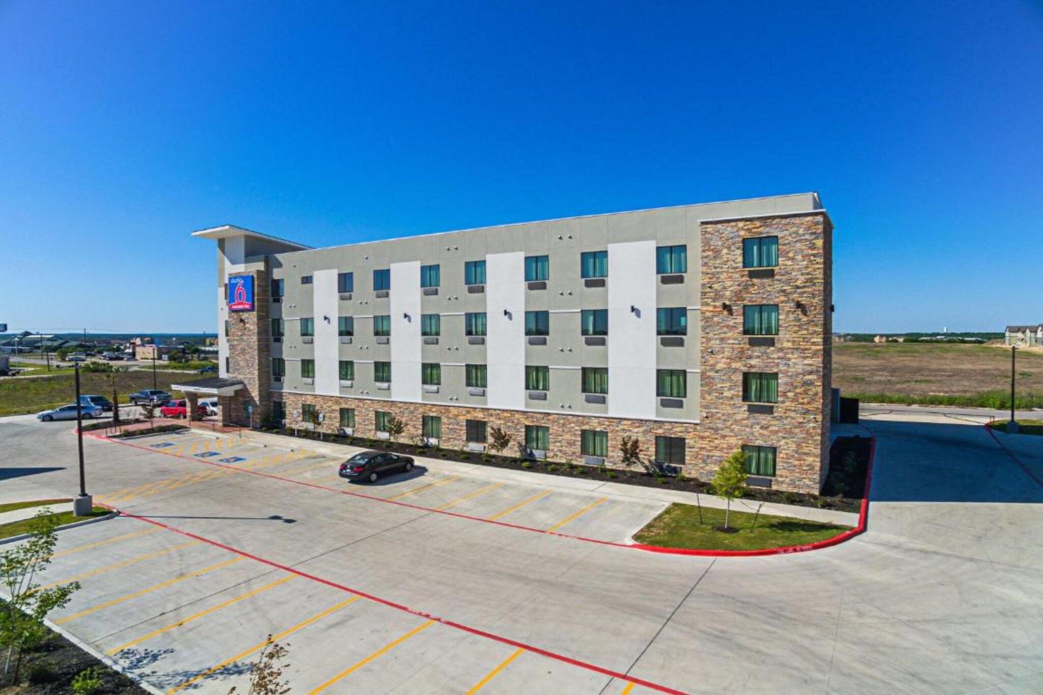 A multi-story hotel with a parking lot in front.