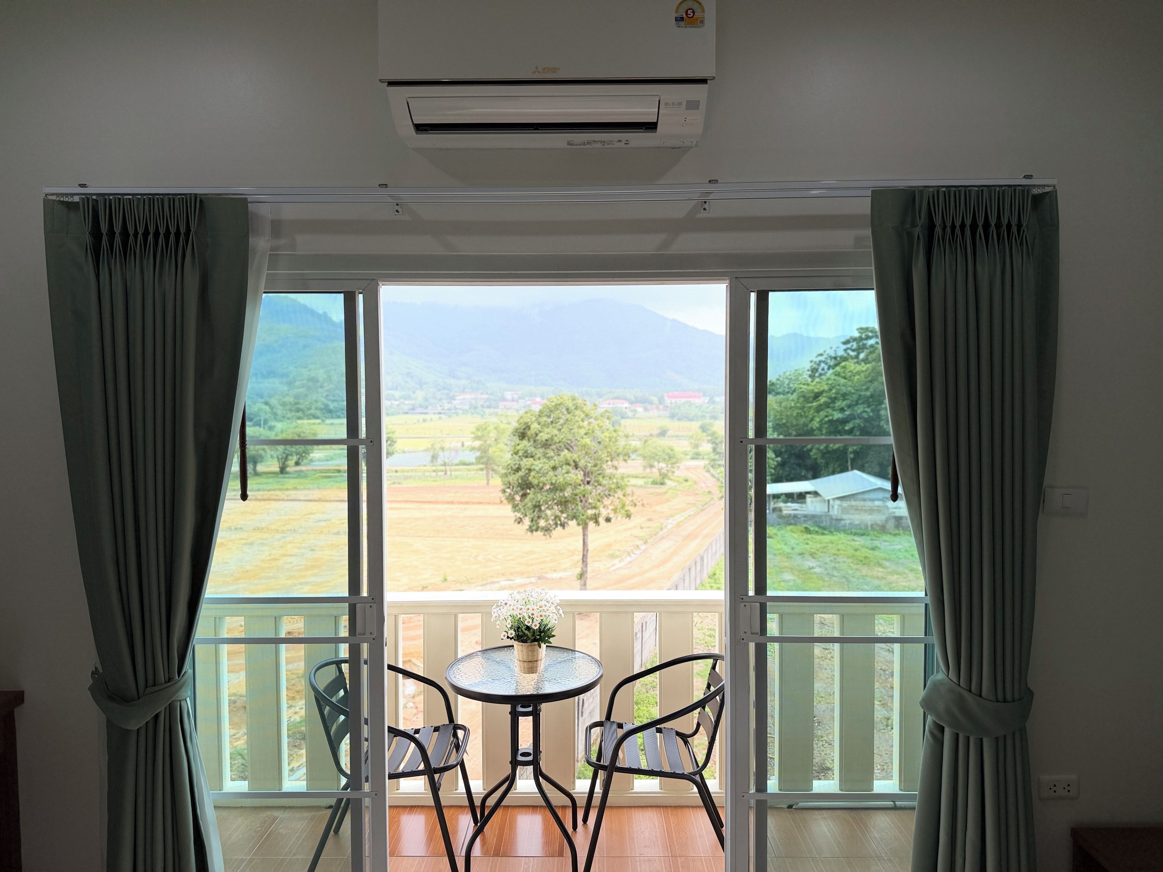 Une pièce avec vue sur un paysage, grâce à de grandes fenêtres, comprenant une table avec des chaises et un appareil de climatisation.