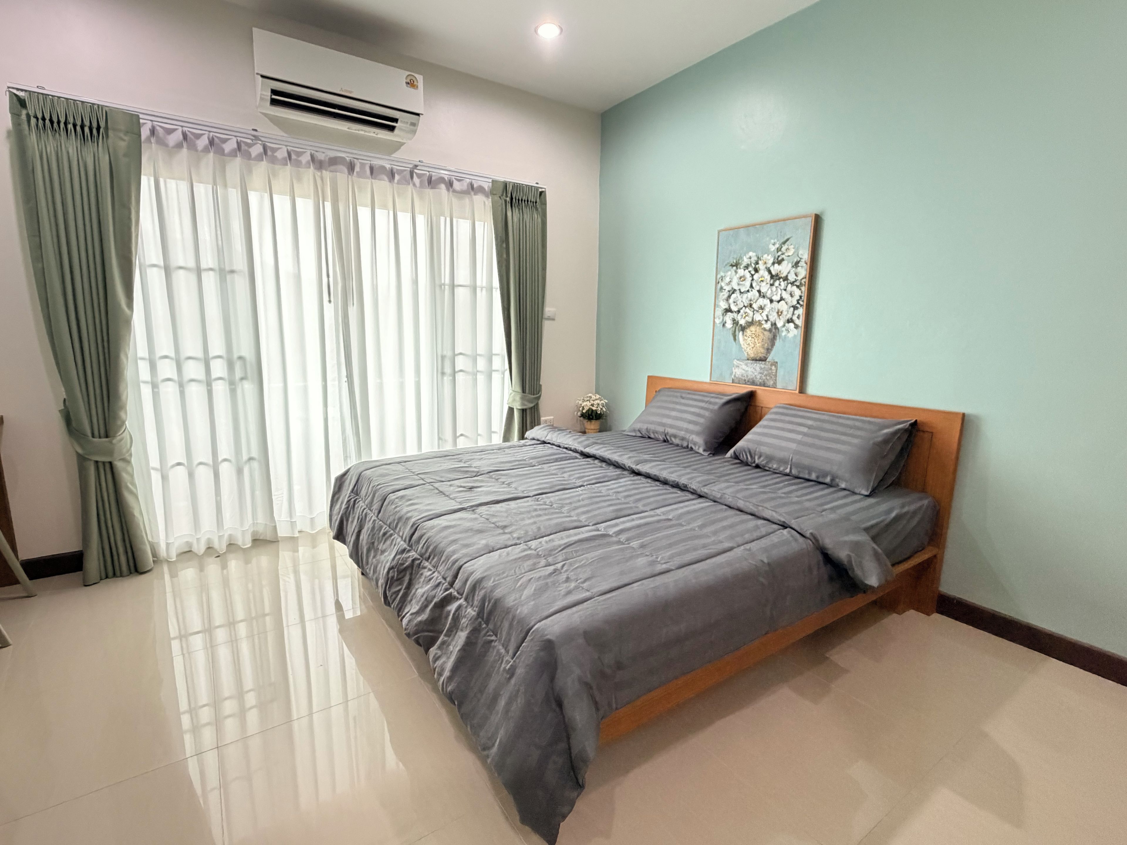 Un dormitorio con cama, cortinas, aire acondicionado y un cuadro en la pared.