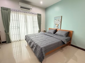 Un dormitorio con cama, cortinas, aire acondicionado y un cuadro en la pared.