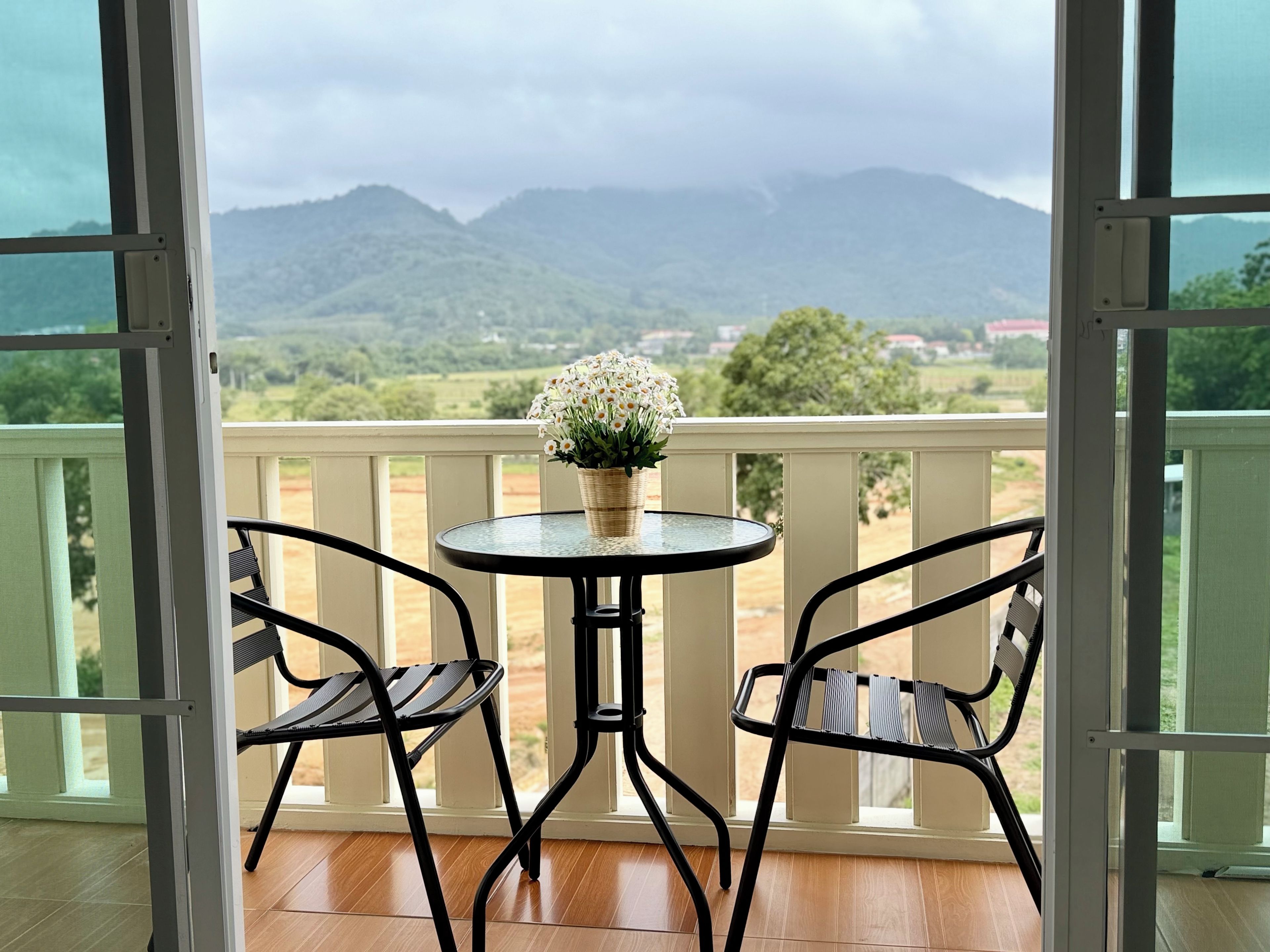 A balcony with a table and chairs, overlooking a mountainous landscape.