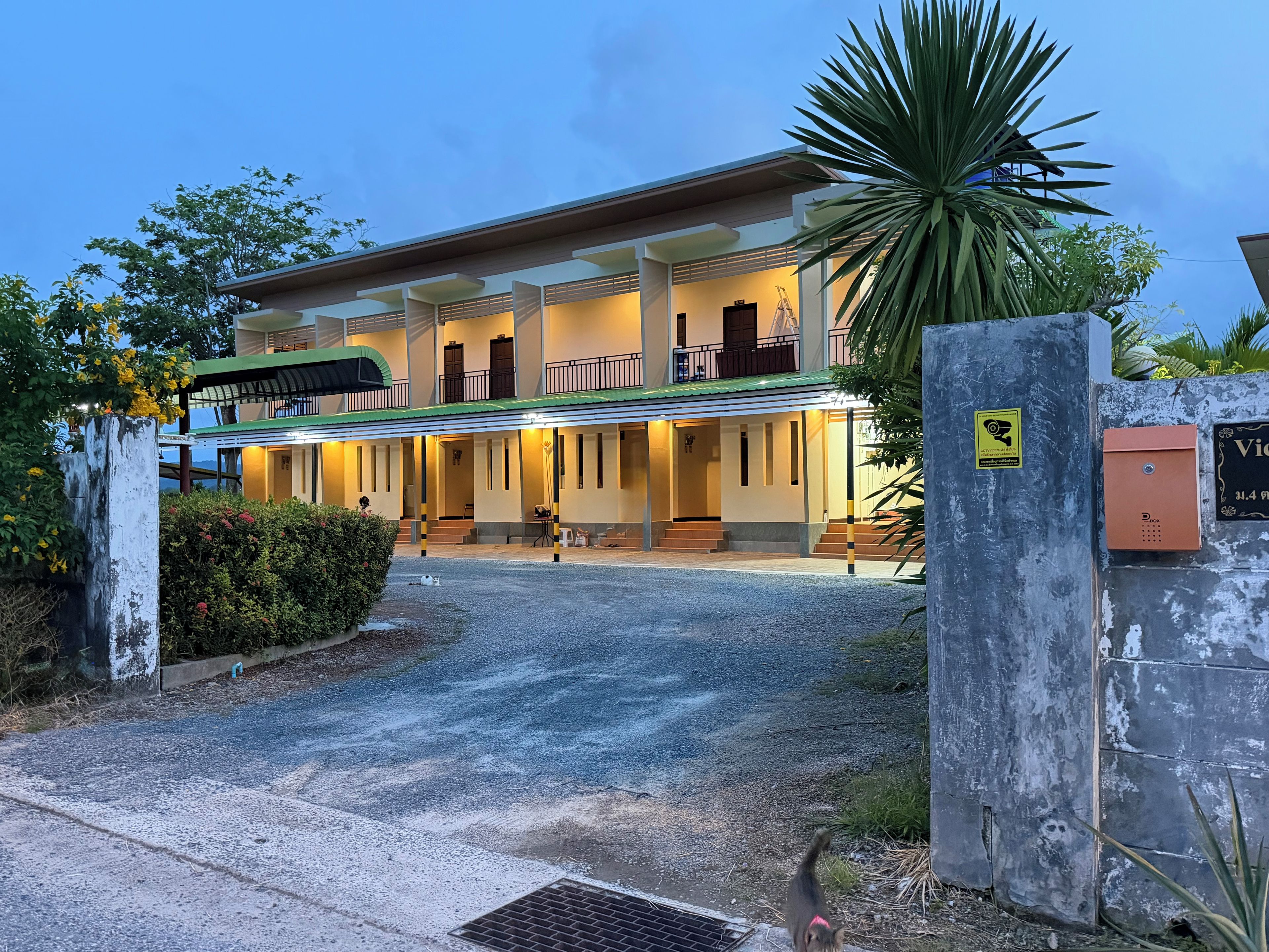 A two-story building with a covered entrance and a gated driveway.