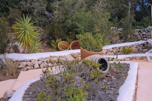 A landscaped garden with various plants and a stone wall.