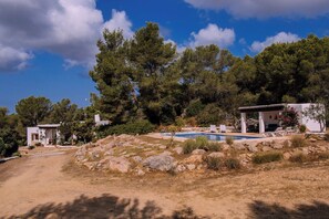 A property with a swimming pool, outdoor seating, and a natural landscape.