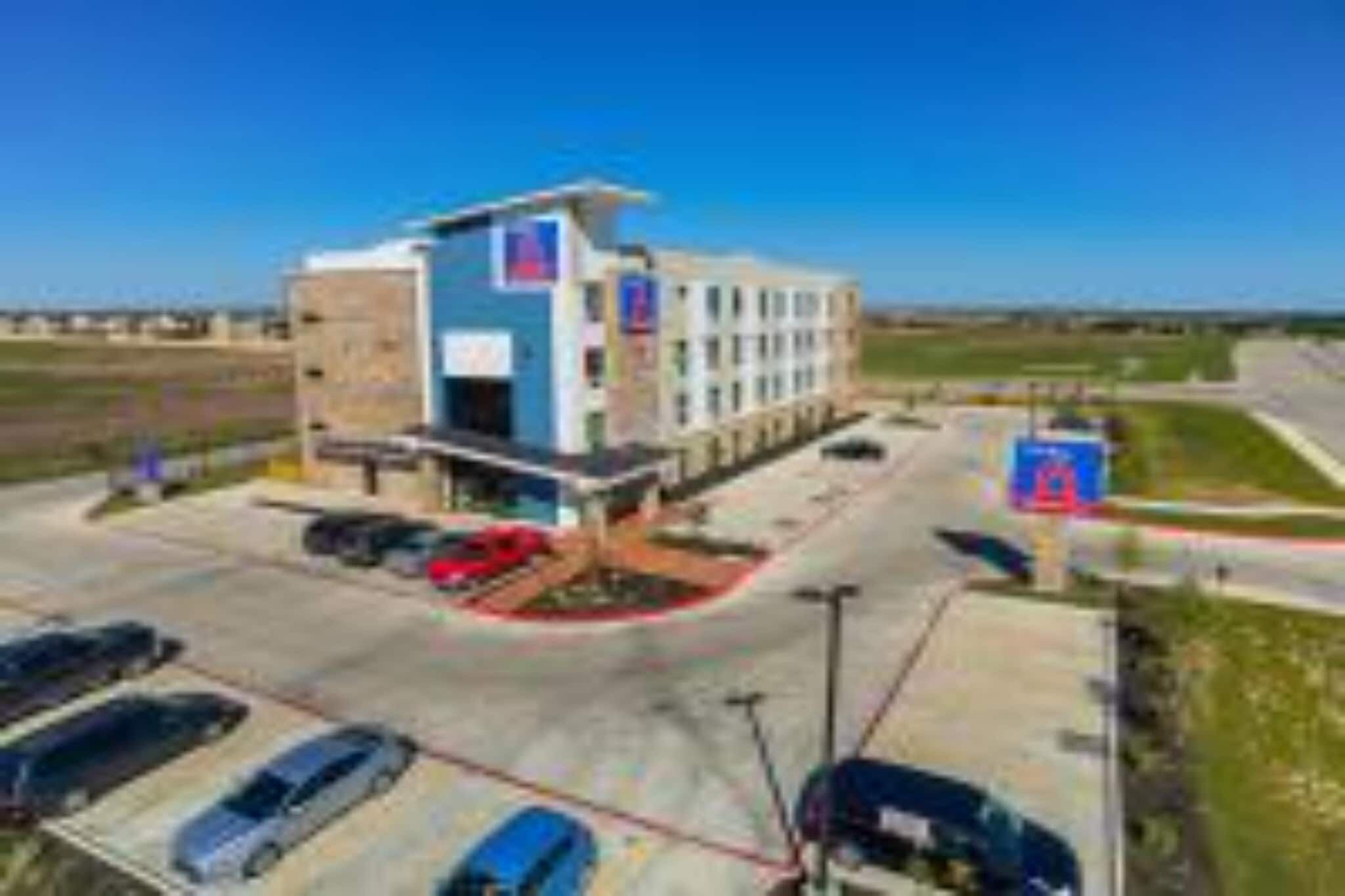 A multi-story building with a parking lot and a clear sky.