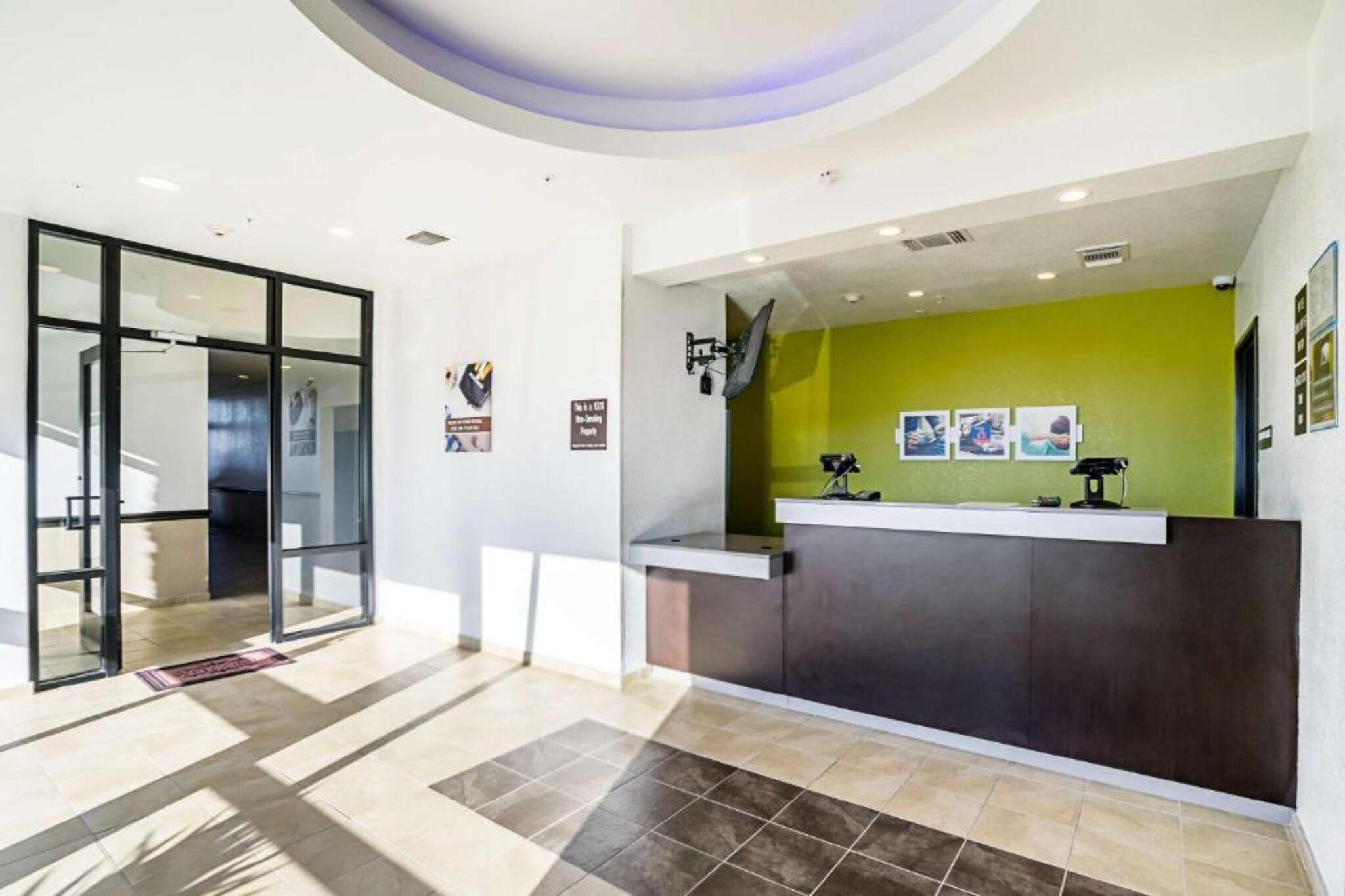 A reception area with a glass door entrance, a reception desk, and a green accent wall.