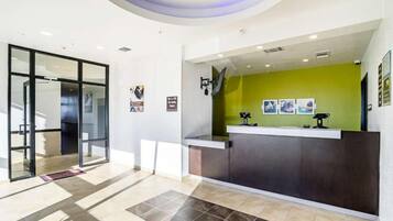 Un área de recepción con puerta de vidrio, un mostrador y una pared de acento verde.