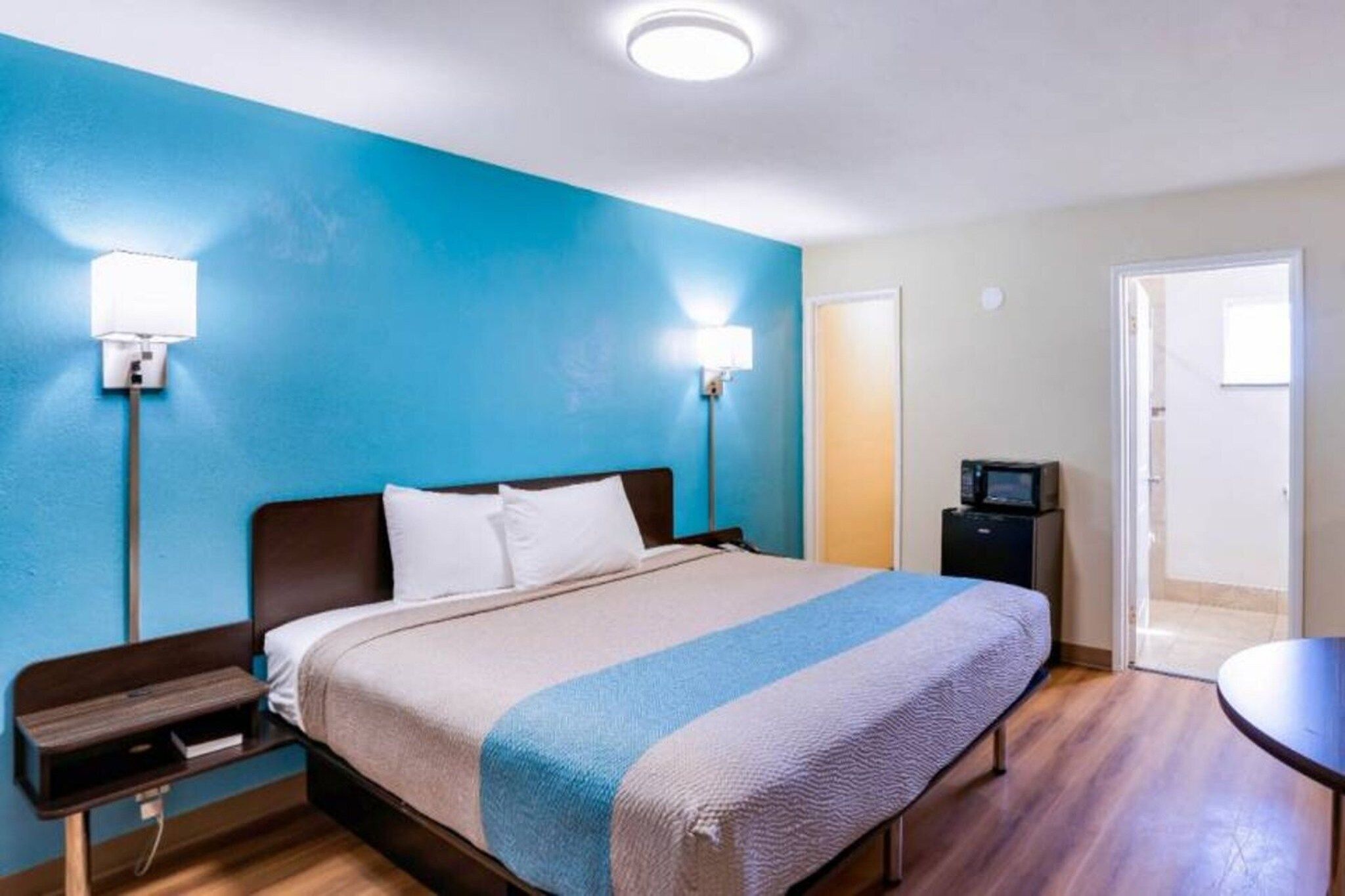 Una habitación de hotel con cama, mesitas de noche, escritorio, silla y televisor.