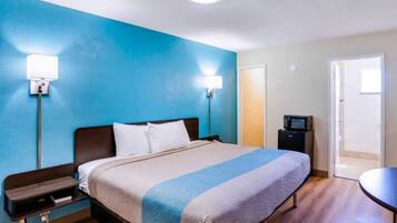 Una habitación de hotel con cama, mesitas de noche, escritorio, silla y televisor.