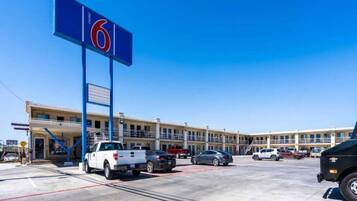 A motel with a large blue sign, multiple parking spaces, and a building with balconies.