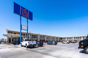 Un motel con un gran letrero azul, varios espacios de estacionamiento y un edificio con balcones.