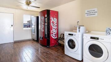 A room with a washing machine, a dryer, and a Coca-Cola refrigerator.