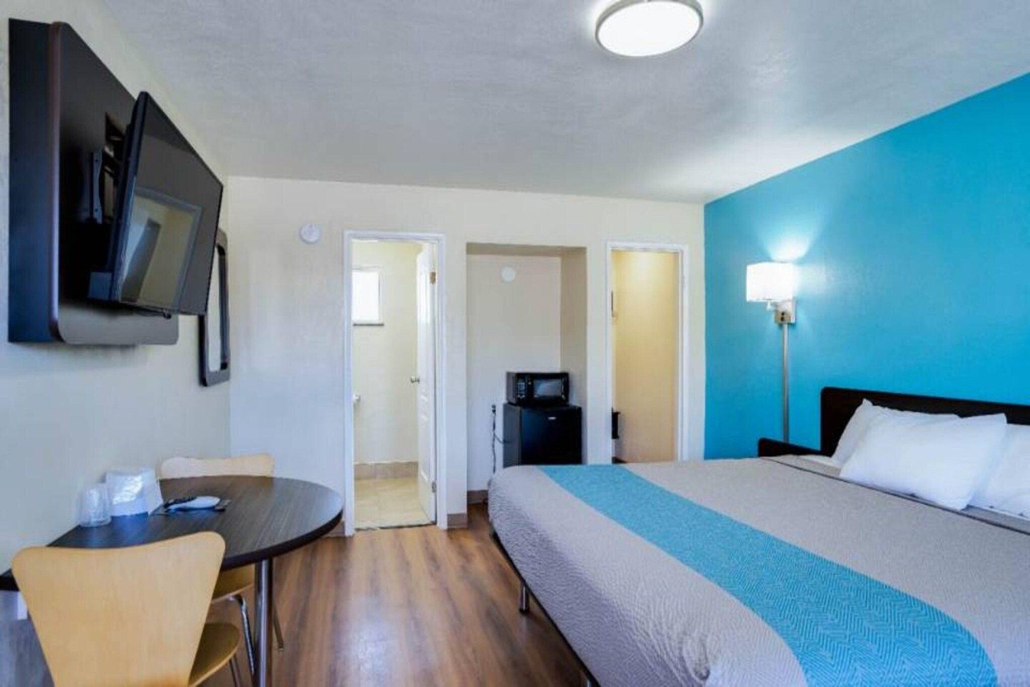A hotel room with a bed, a desk, a chair, a television, and a microwave.