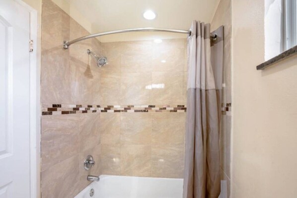 A bathroom with a shower, a bathtub, and a tiled wall. - 1 King Bed | Non-Smoking, Micfridge (Odessa TX)
