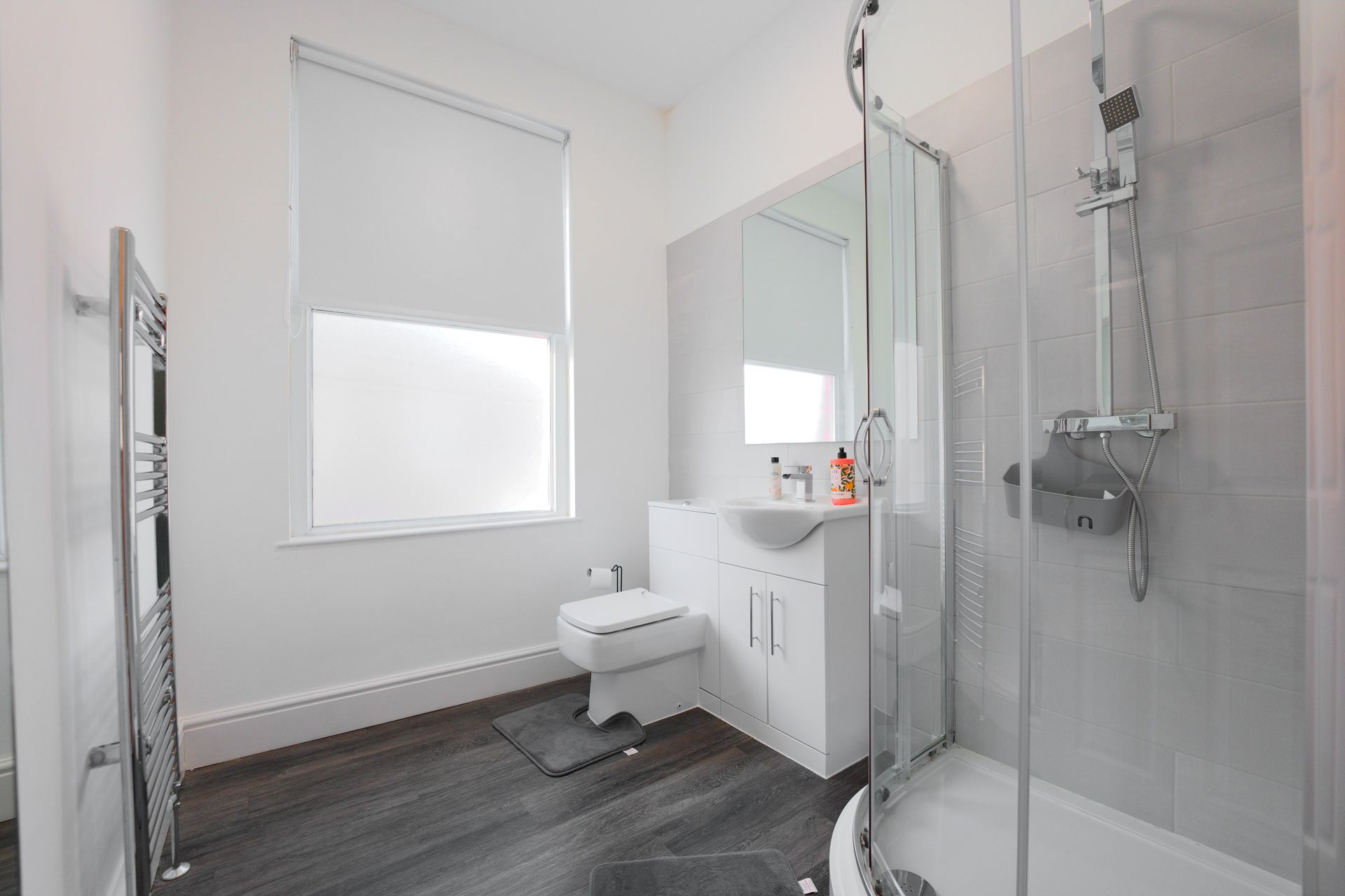 A modern bathroom with a glass shower enclosure, a white sink, and a toilet.