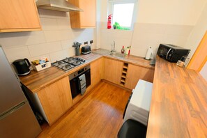 Een kleine keuken met een gasfornuis, oven, spoelbak en een magnetron.