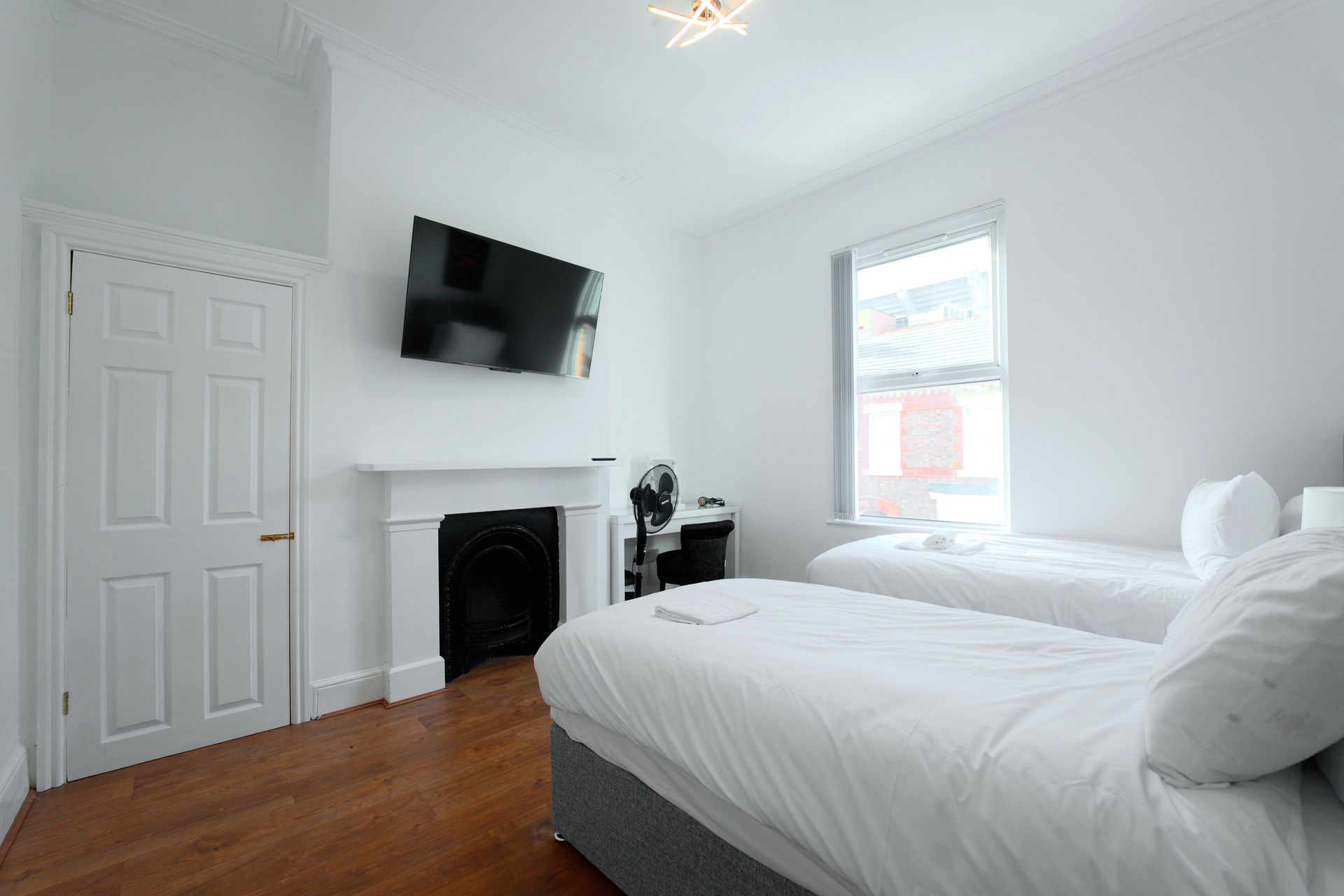 Een slaapkamer met twee bedden, een open haard, een televisie en een raam.