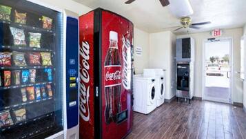 A room with vending machines, a washing machine, and an exit sign.