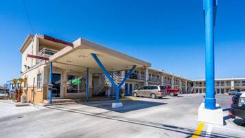 A gas station with a covered fuel pump area, multiple cars parked, and a clear blue sky.