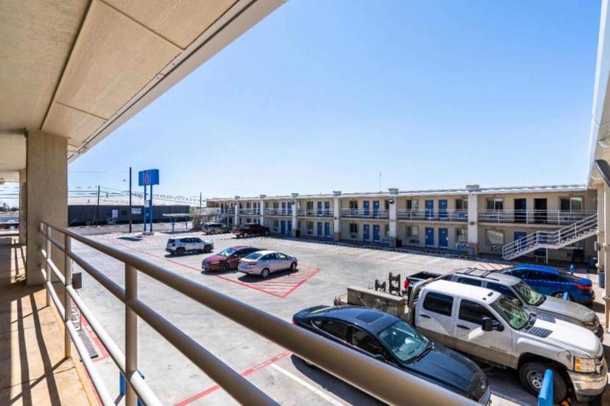 A parking lot with multiple cars and a building with multiple floors and balconies.