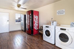 Et værelse med vaskemaskine, tørretumbler og et Coca-Cola køleskab.