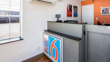 A reception desk with a digital display, a window with blinds, and a door.