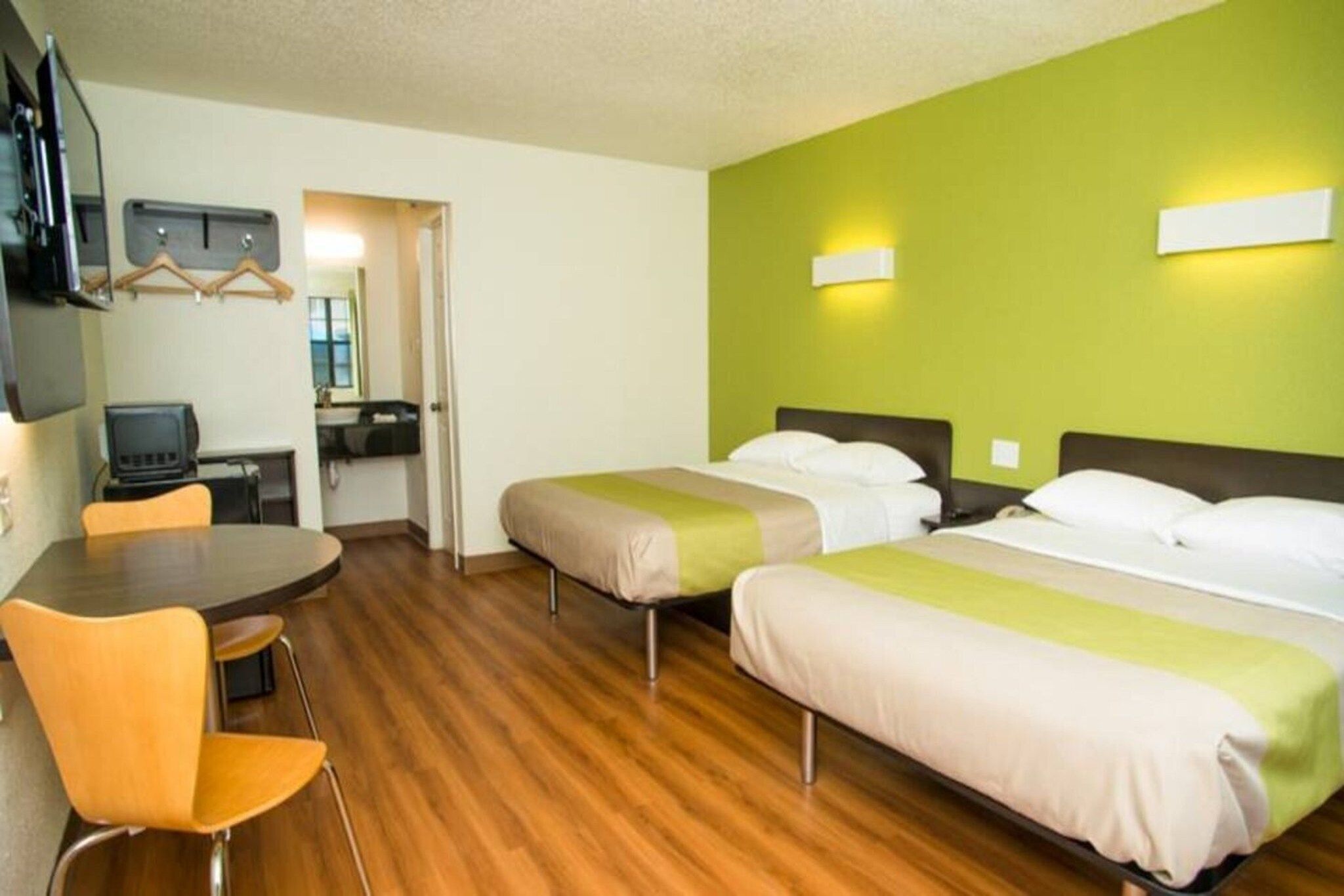 Habitación de hotel con dos camas, un escritorio, una silla y un televisor.