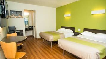 Habitación de hotel con dos camas, un escritorio, una silla y un televisor.