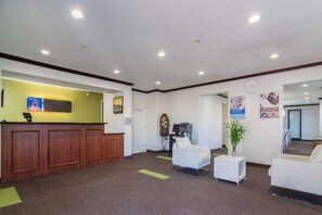 A reception area with a wooden desk, a green wall, and a clock on the wall. - 1 Twin Bed | Mobil Access Tub Nsmk Micfridg (Plano)