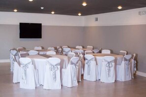 Una sala de conferències amb taules i caires, un televisor de pantalla plana muntat a la paret i una decoració amb tons neutres.