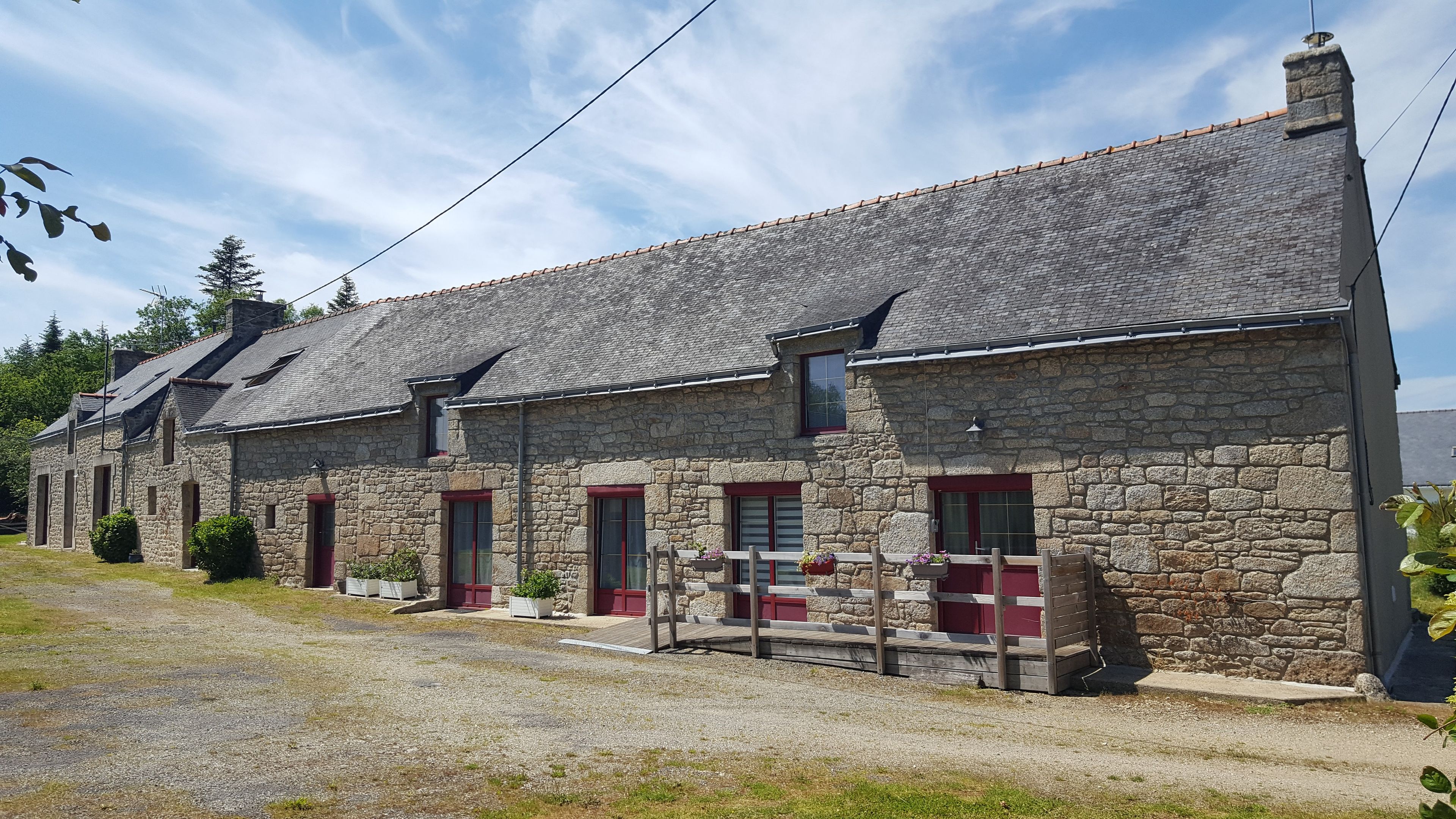 A stone building with multiple windows and doors, a gravel driveway, and a small porch area.
