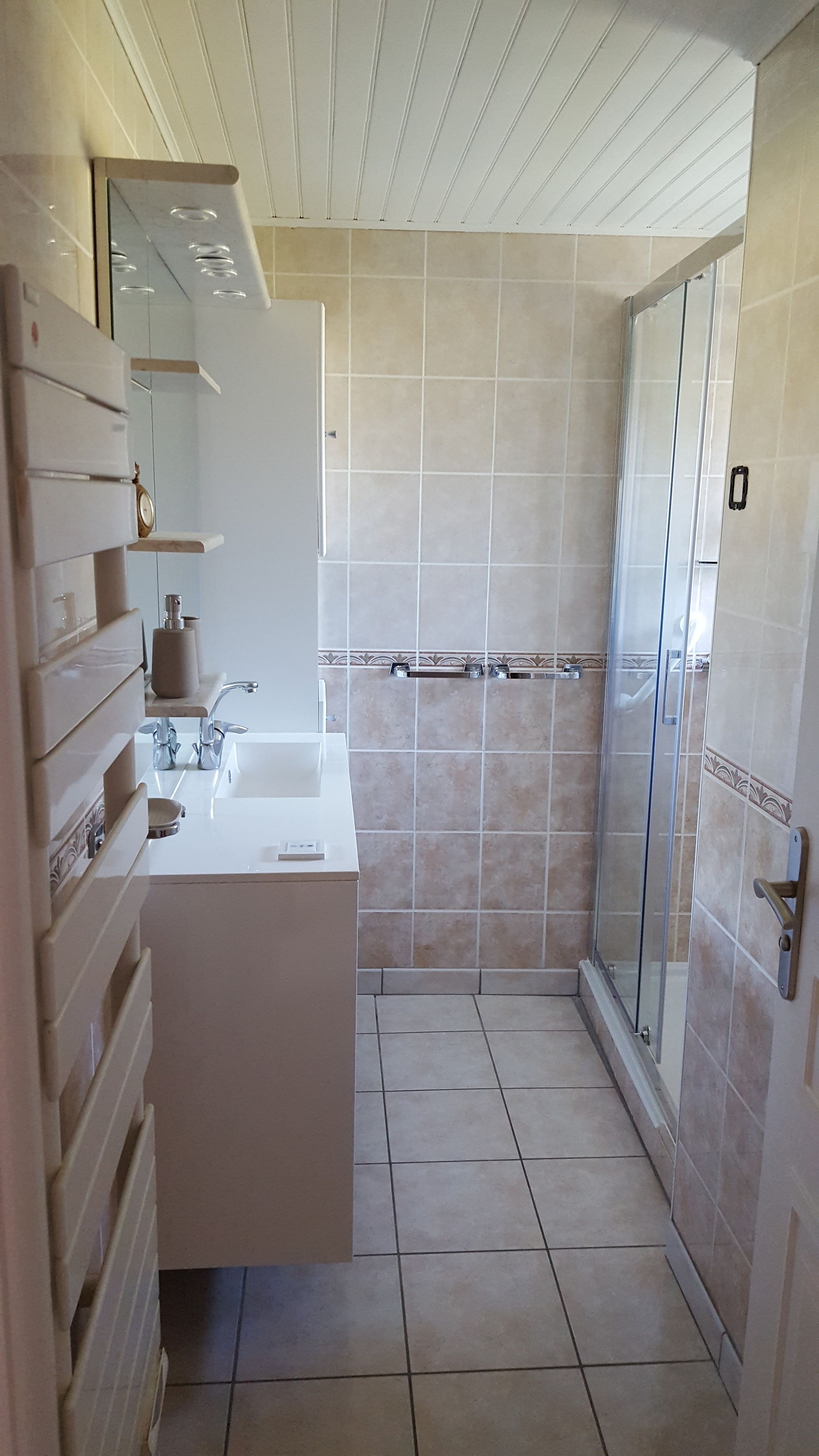 Een badkamer met een wit wastafelmeubel, spiegel en handdoekhouder.