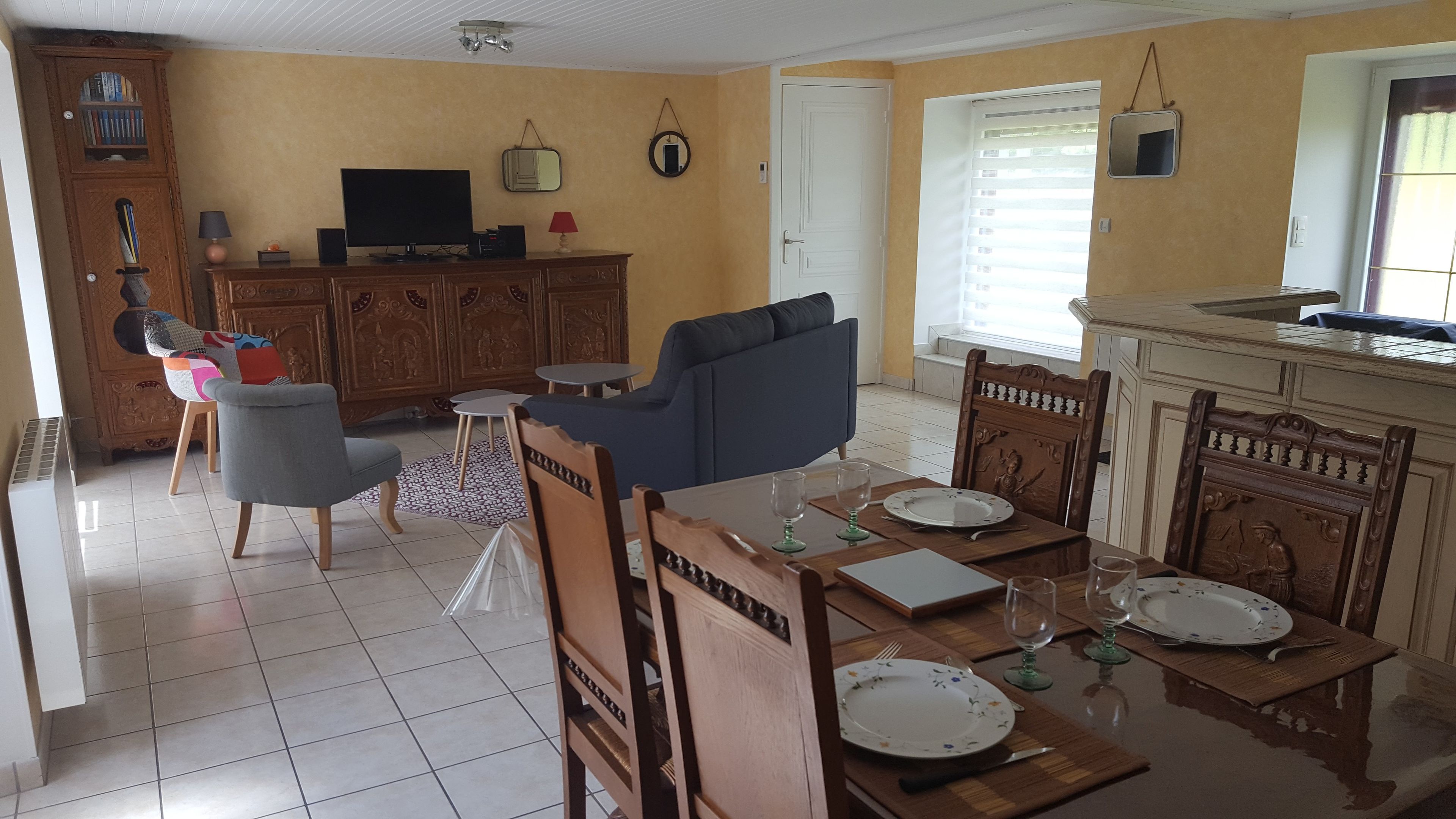 A living room with a sofa, a TV, and a dining area with a table set for two.