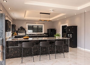 Een moderne keuken met een groot schiereiland, barstoelen en een inbouwoven.