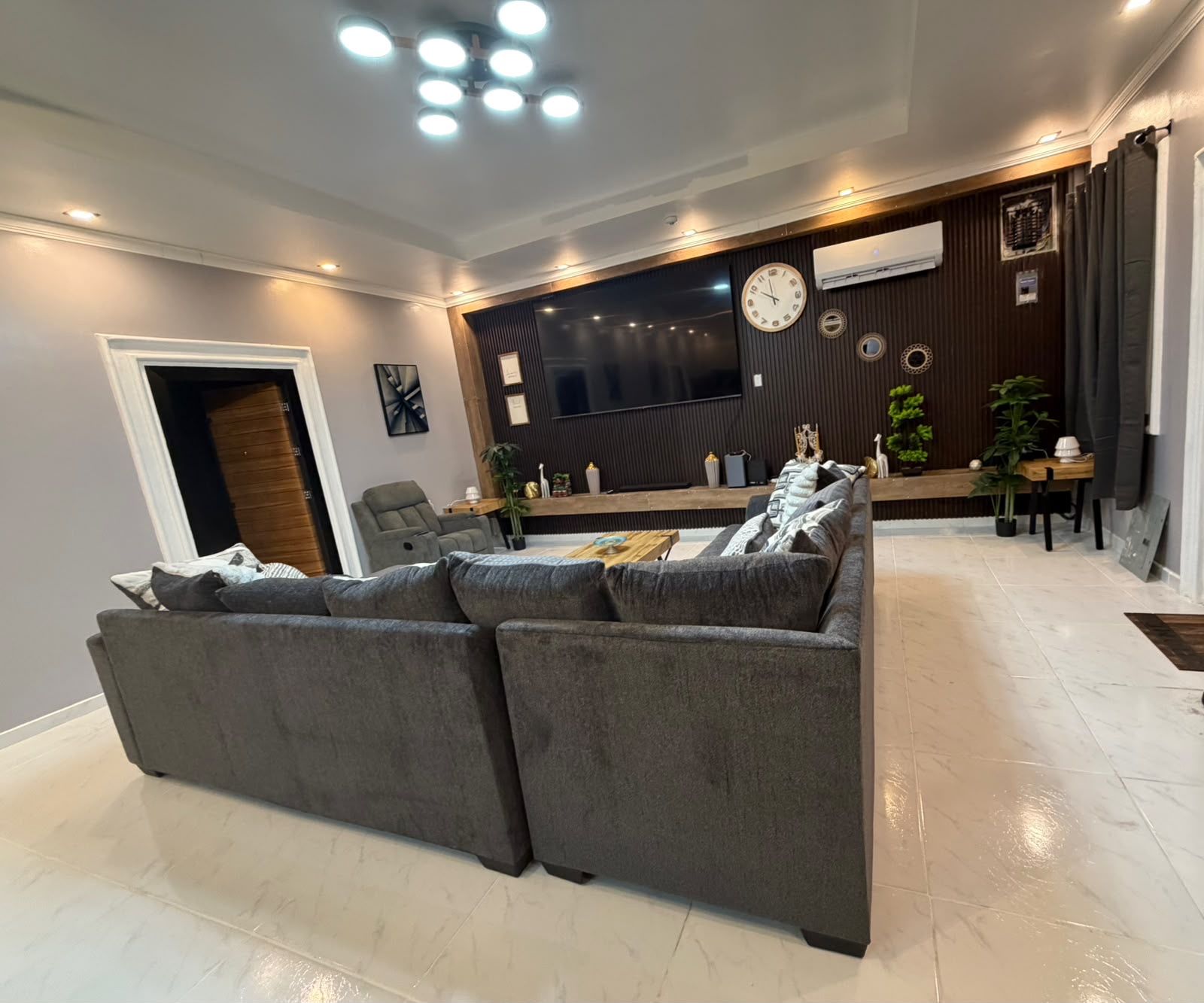 Un salon moderne avec un canapé gris, un téléviseur à écran plat et un meuble de rangement en bois.
