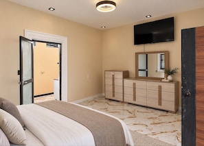 Een slaapkamer met een bed, een dressoir, een spiegel en een televisie aan de muur.