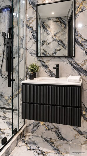 Een moderne badkamer met een douchecabine van glas, een zwart wastafelmeubel en wanden met een marmerlook.