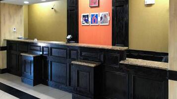 Zona de recepción con mostrador, paneles de madera oscura y una pared con cuadros enmarcados.